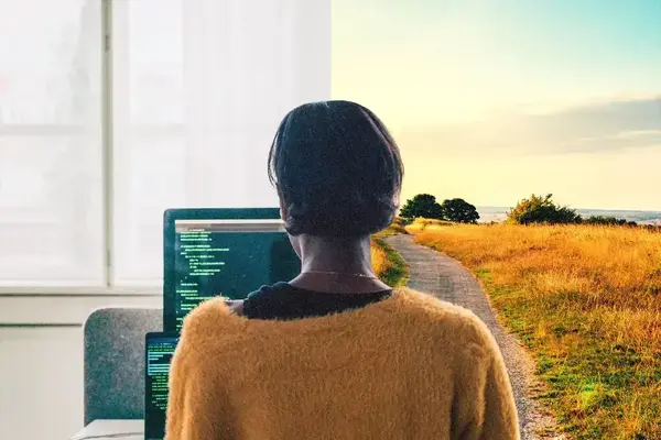 A woman looks at a computer screen, with a walking path on the right side of the photo